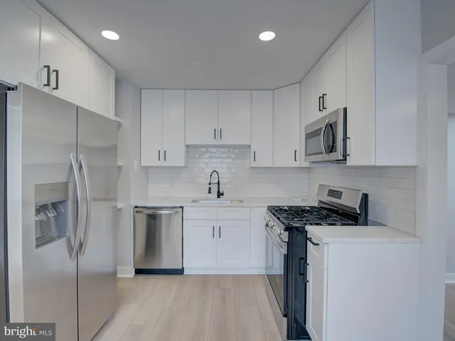 a kitchen with stainless steel appliances white cabinets and a refrigerator