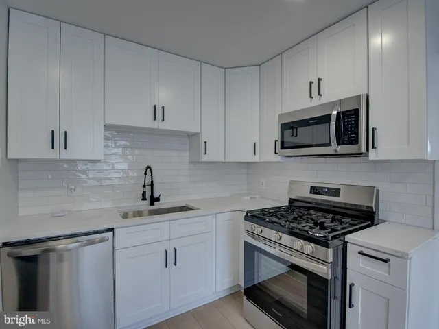 a kitchen with white cabinets stainless steel appliances and sink