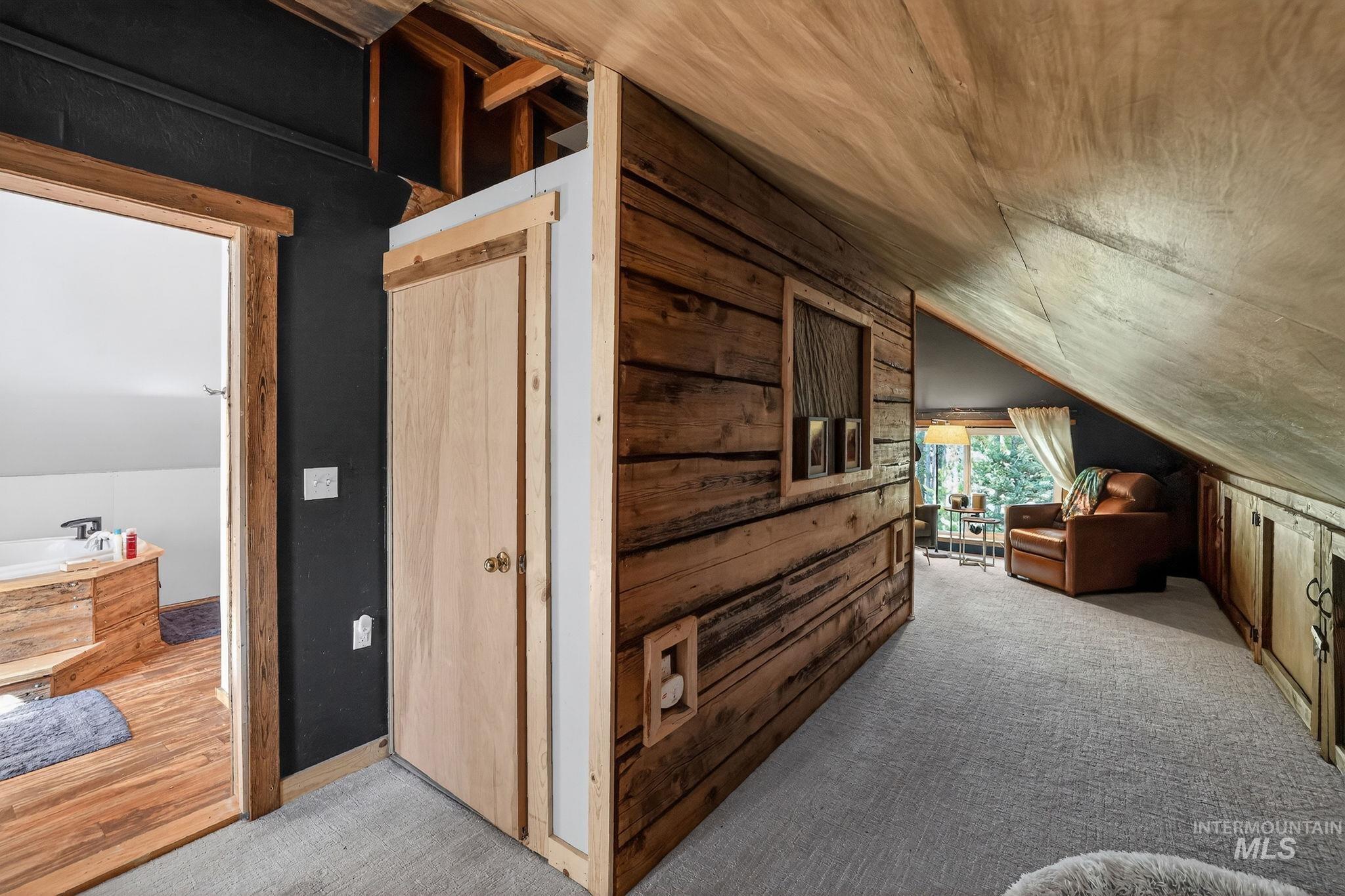 321 Secesh River Road McCall, ID 83638 - Photo 14 of 50 Carpeted loft area featuring a natural wood-paneled wall, angled wood-paneled ceiling, and a built-in wood-framed window