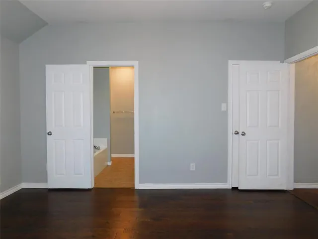 a view of an empty room with wooden floor and closet