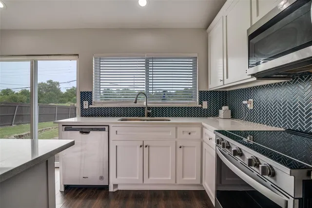 a kitchen with white cabinets and appliances