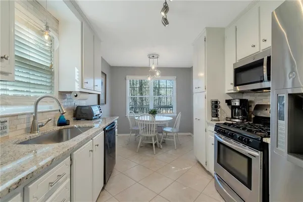 a kitchen with granite countertop a sink stainless steel appliances and cabinets