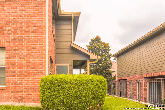 a view of a brick house with a yard and plants