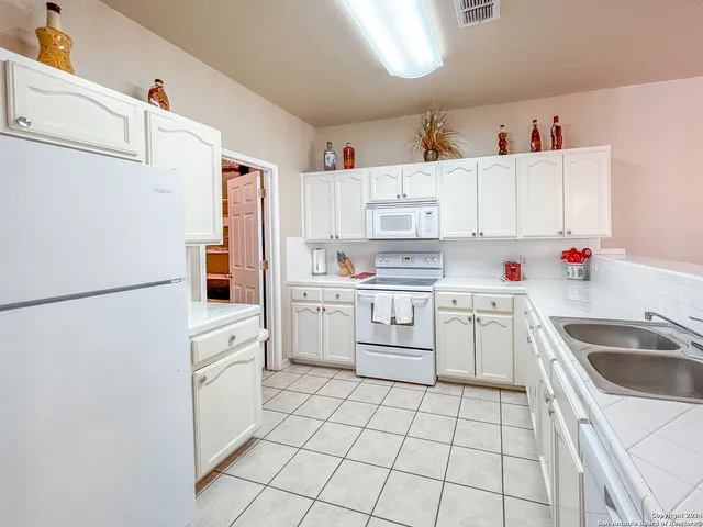 a kitchen with white cabinets a sink and white appliances