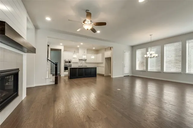 a view of an empty room with wooden floor and a kitchen