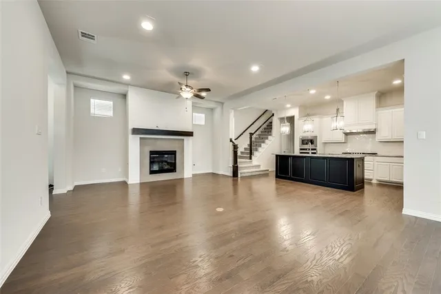 an empty room with wooden floor and a kitchen