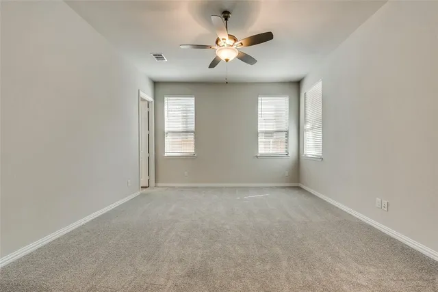 an empty room with windows and ceiling fan