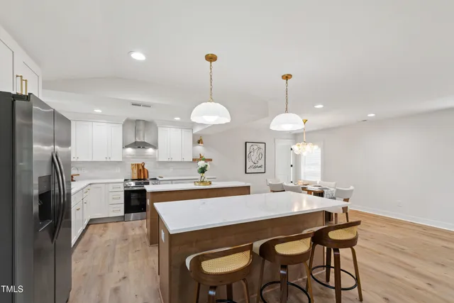 a kitchen with stainless steel appliances a dining table chairs stove refrigerator and microwave