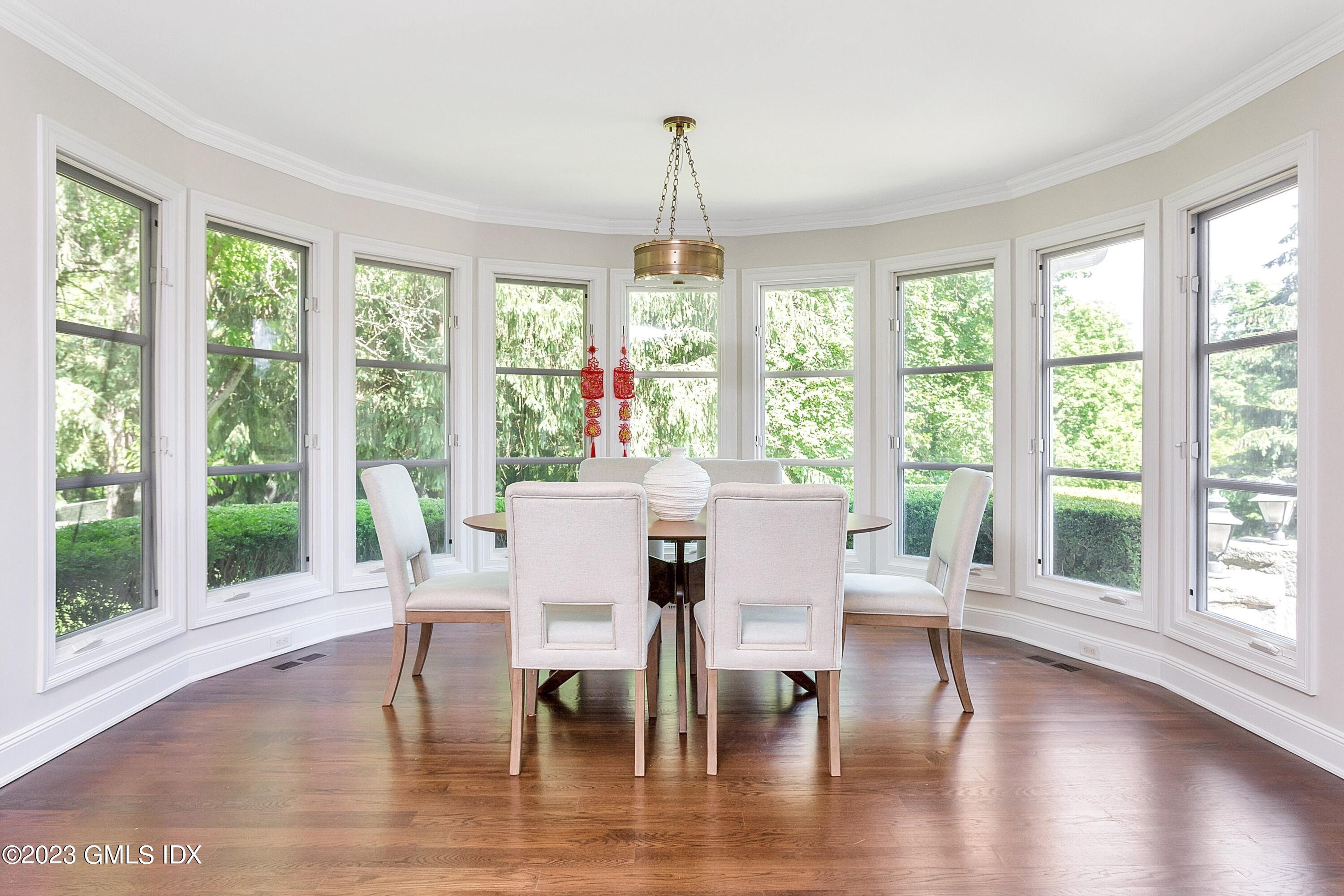 357 Round Hill Road Greenwich, CT 06831 - Photo 13 of 52 a dining room with wooden floor a chandelier a glass table and chairs