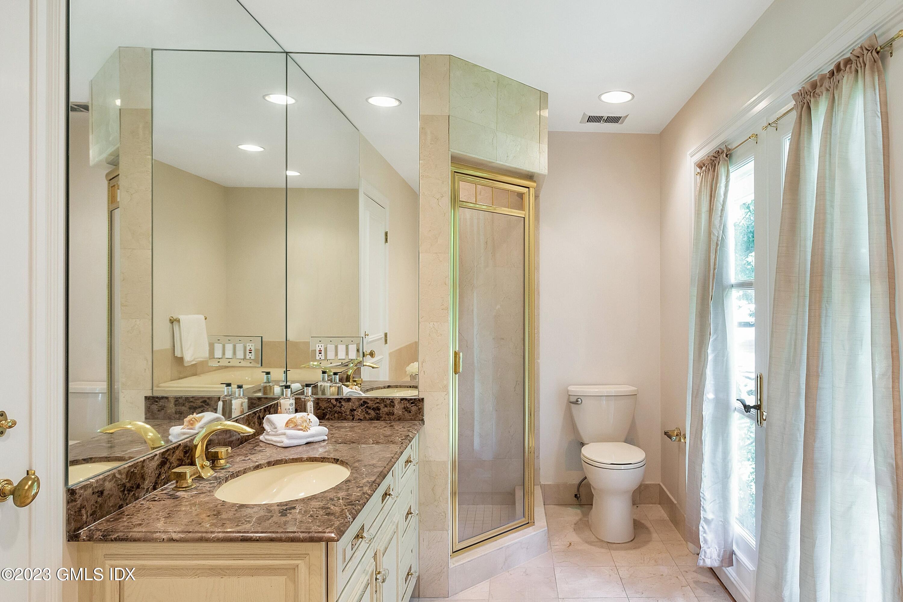 357 Round Hill Road Greenwich, CT 06831 - Photo 20 of 52 a spacious bathroom with a granite countertop sink a toilet and a large mirror