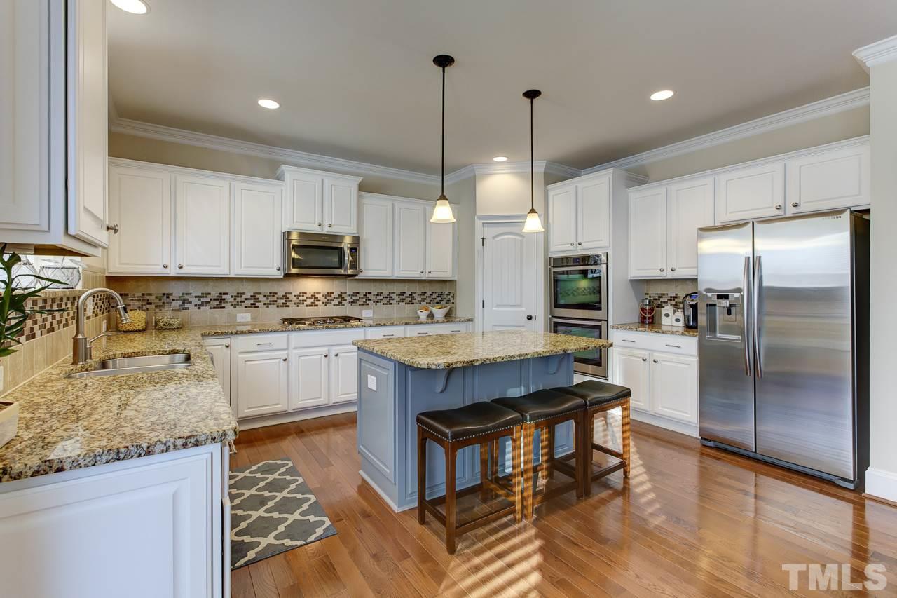 7319 Litchford Road Raleigh, NC 27615 - Photo 4 of 25 a kitchen with kitchen island granite countertop a stove a sink a refrigerator a center island and cabinets