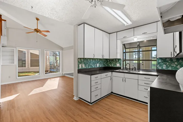 a kitchen with granite countertop a stove a sink and white cabinets with wooden floor