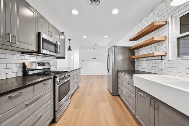 a large kitchen with stainless steel appliances granite countertop a lot of counter space and a sink
