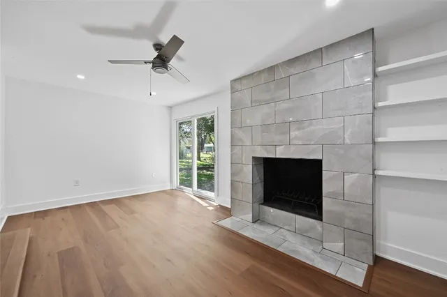 a view of an empty room with wooden floor fireplace and a window