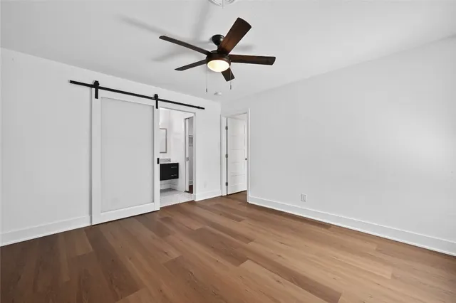 a view of an empty room with wooden floor and a ceiling fan