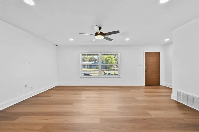 an empty room with windows and fan