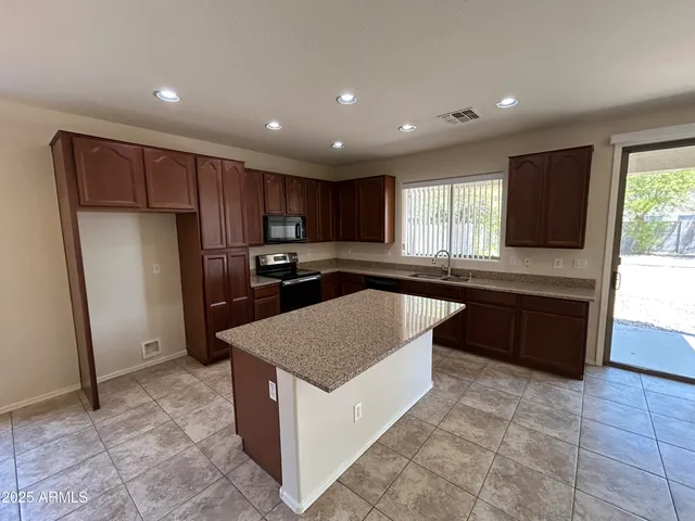 a kitchen with stainless steel appliances granite countertop a stove a sink and a refrigerator