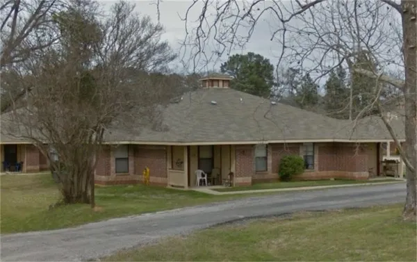 a front view of a house with a garden and trees