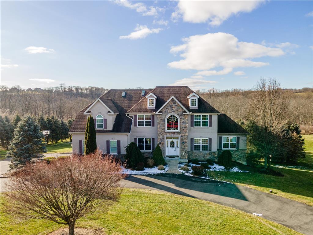 a view of a house next to a big yard and large trees