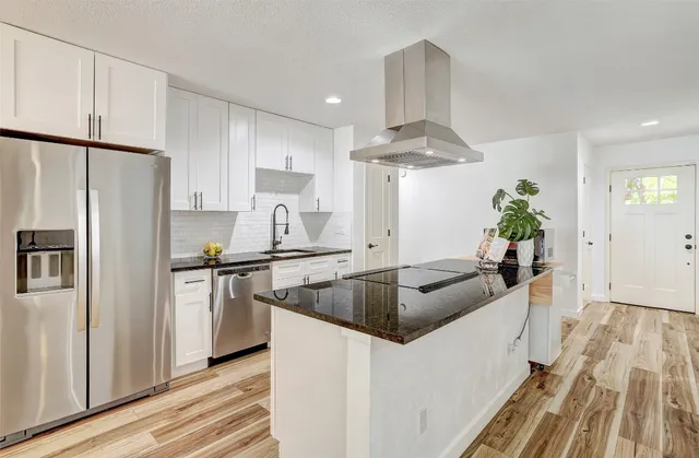 a kitchen with kitchen island a counter top space a sink stainless steel appliances and cabinets