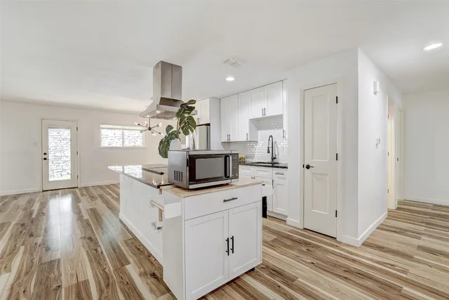 a view of kitchen with wooden floor electronic appliances and windows