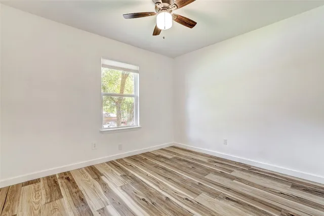 a view of empty room with window and ceiling fan