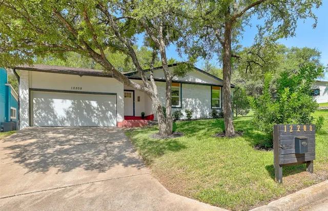 a view of a house with a small yard and a large tree