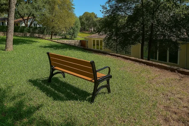 a view of a bench in the garden near a house