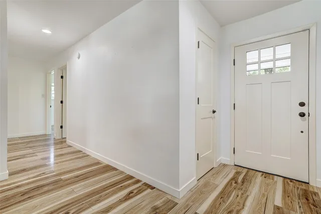a view of a hallway with wooden floor and a bathroom