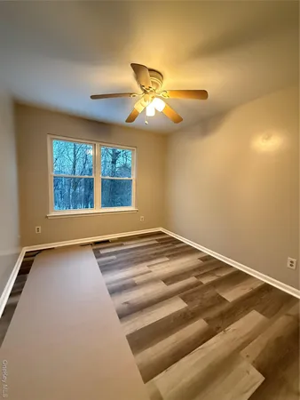 a view of an empty room with window and chandelier fan