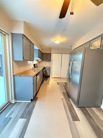 a kitchen with stainless steel appliances granite countertop a refrigerator a sink and wooden floors