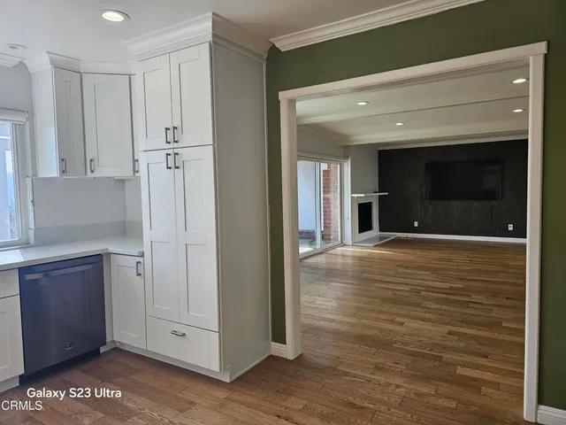 a view of a hallway with wooden floor and cabinet