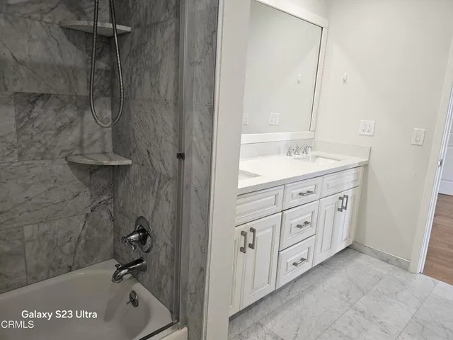 a spacious bathroom with a granite countertop sink mirror and bathtub