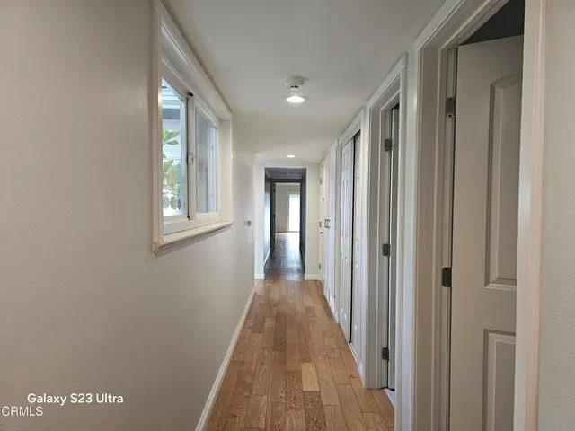 a view of a hallway with wooden floor and a window