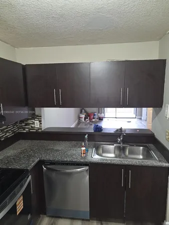 a kitchen with a sink and a stove with wooden cabinets