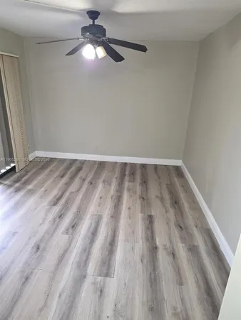 an empty room with wooden floor fan and window