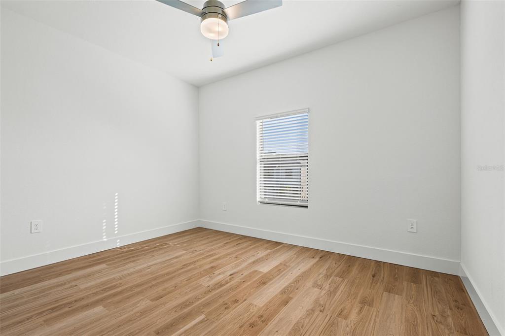 8025 Gulfstream Court Lakewood Ranch, FL 34202 - Photo 35 of 44 an empty room with wooden floor fan and windows