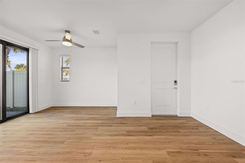 8025 Gulfstream Court Lakewood Ranch, FL 34202 - Photo 9 of 44 a view of an empty room with wooden floor and a ceiling fan