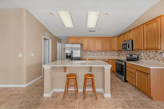 an empty room with a chandelier fan and windows