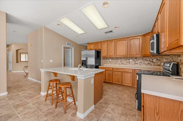 a view of an empty room with window and a kitchen view