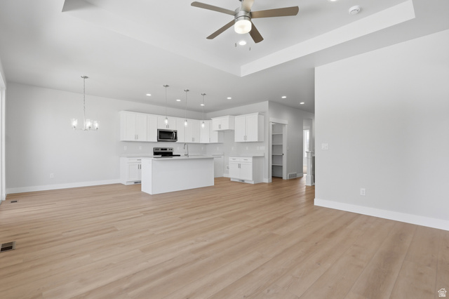 677 East 800 S Street Springville, UT 84663 - Photo 2 of 35 Unfurnished living room featuring a tray ceiling, hanging lights, light wood finished floors, and ceiling fan