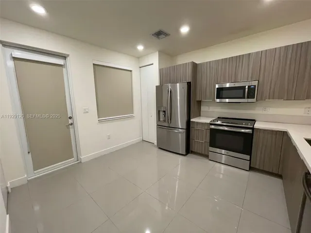a kitchen with a sink a counter top space cabinets and stainless steel appliances