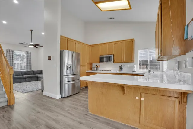 a kitchen with stainless steel appliances granite countertop a refrigerator a sink dishwasher a oven with white cabinets and wooden floor