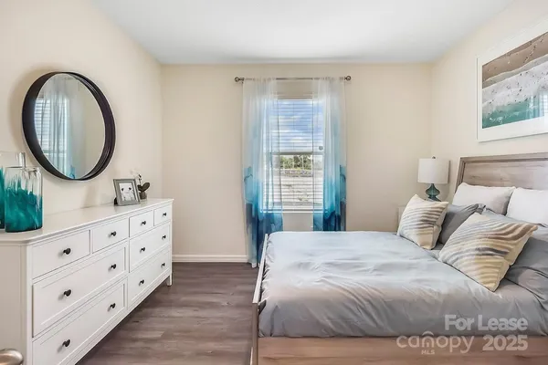 a bedroom with a bed a mirror on dresser and a window