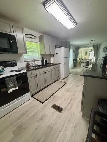 a kitchen with stainless steel appliances granite countertop a stove a sink dishwasher and a refrigerator with wooden floor