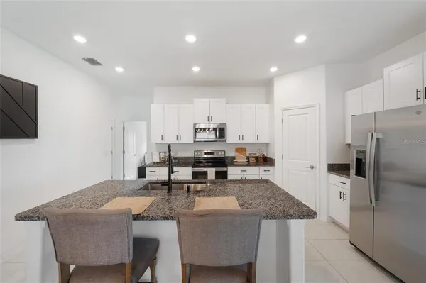 a kitchen with stainless steel appliances granite countertop a sink a stove a refrigerator with a dining table and chairs