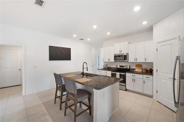a kitchen with stainless steel appliances granite countertop a stove a sink a microwave a refrigerator and a refrigerator