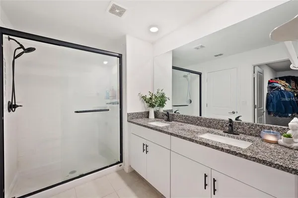 a bathroom with a granite countertop shower sink and mirror