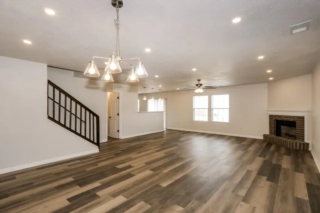 a view of a livingroom with a fireplace a chandelier and wooden floor