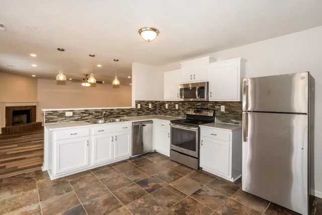 a kitchen with granite countertop a refrigerator and a stove top oven